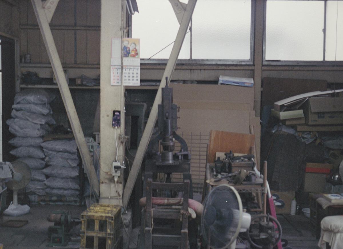 The Negishi workshop in Sumida with steel uprights, stacked sandbags and metalworking machinery