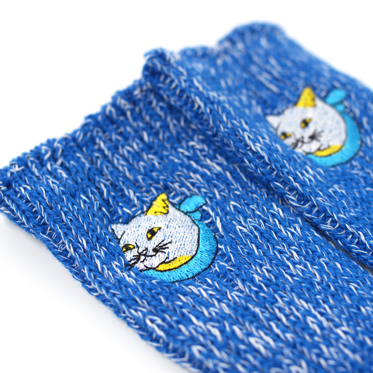 Close-up of the embroidered white cat on the blue marled knit of each sock